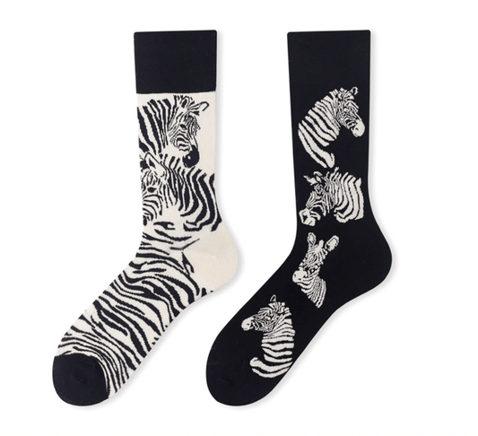 A pair of mismatched socks featuring zebra patterns in black and white.